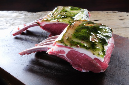 uncooked rack of lamb on wooden board