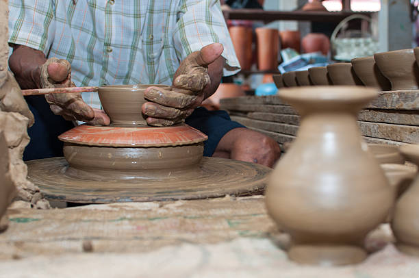 istock man shapes pottery as it turns on a wheel 466354413