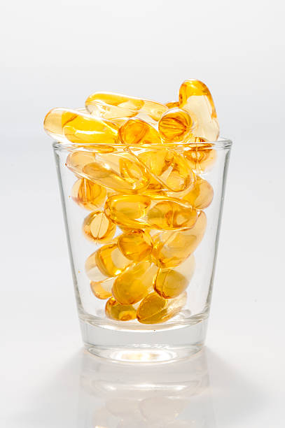 fishoil - capsule pill vitamin e shot glass photos et images de collection