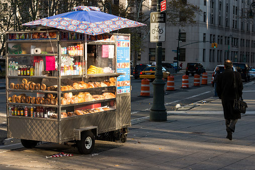 New York, USA - November 18, 2014: A hot dog cart early in the morning as a man passes in the Wall Street area of Lower Manhattan. 