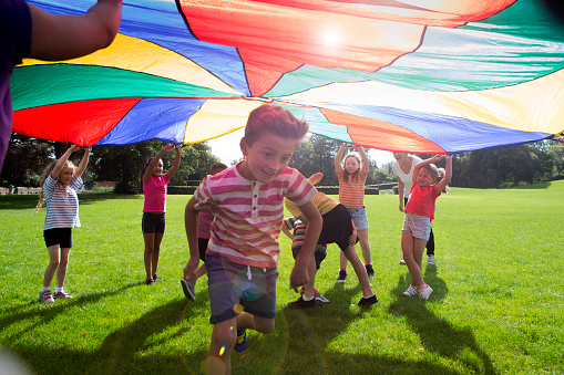 Children playing a game with a colourful Parachute
