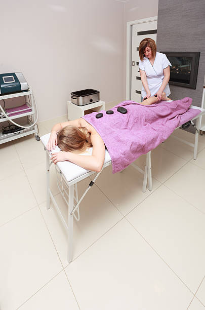 ビューティーサロンも備えています。 女性スパのホットストーンセラピーマッサージ - massage therapist stone spa treatment working ストックフォトと画像