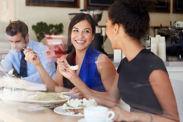 dos mujeres de negocio para reuniones durante el almuerzo en la cafetería - business meeting business lunch business person fotografías e imágenes de stock