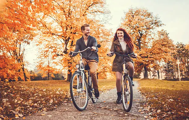 Photo of Young redhead couple cycling during autumn day.