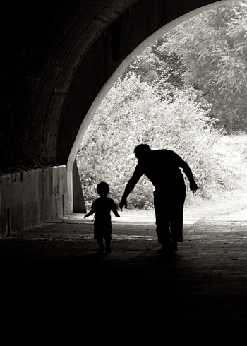 A man and boy silhouette in a tunnel