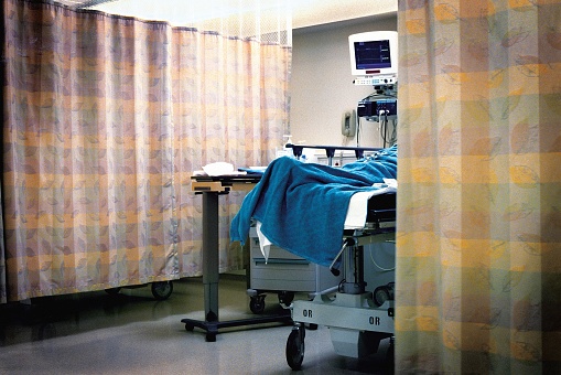 A hospital room with the curtain pulled for the second bed.