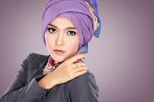 Fashion portrait of young beautiful muslim woman with purple costume wearing hijab