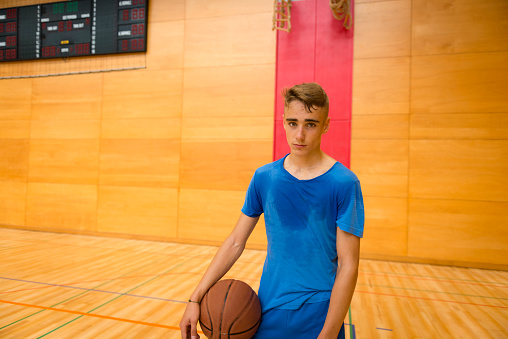 An exhausted teenager posing with a basketball in the school gymnasium, Europe. Nikon D800, full frame, XXXL.