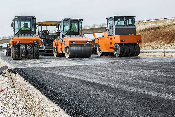 Road Construction Pavement machine laying fresh asphalt or bitumen on top of the gravel base during highway construction drudgery photos stock pictures, royalty-free photos & images