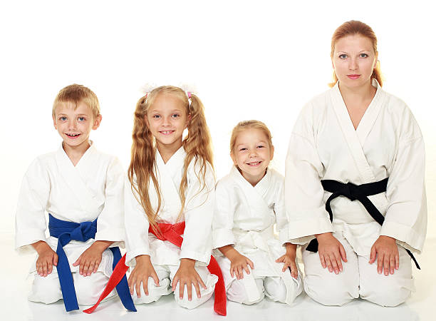 istock Boy with sister, mother with daughter sitting in karate pose 466386609