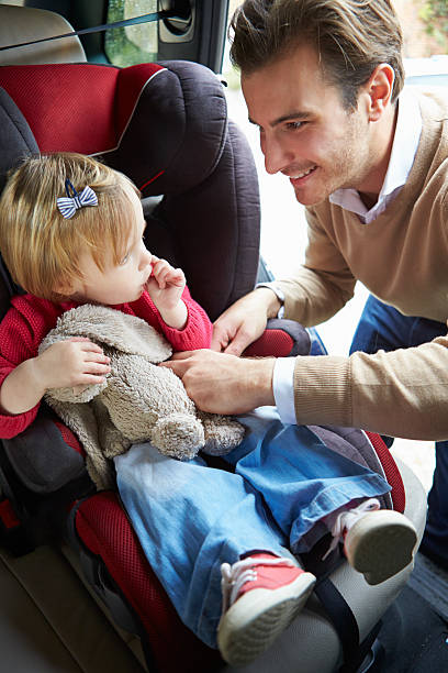 istock Father Putting Young Girl Into Car Seat 466386697