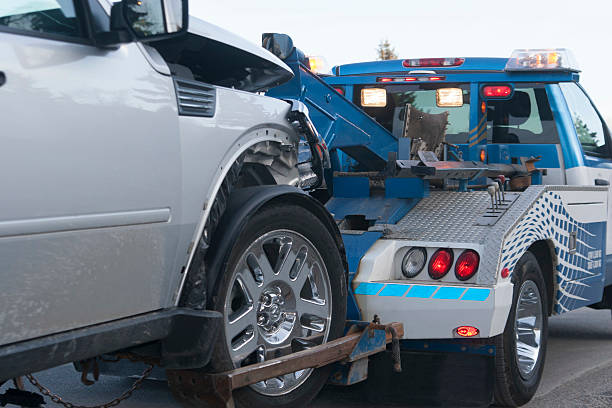 Tow Truck Wreck A damaged new vehicle on a tow truck. Medium shot. medium shot stock pictures, royalty-free photos & images