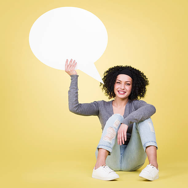 Happy girl holding a blank speech balloon with copy space.