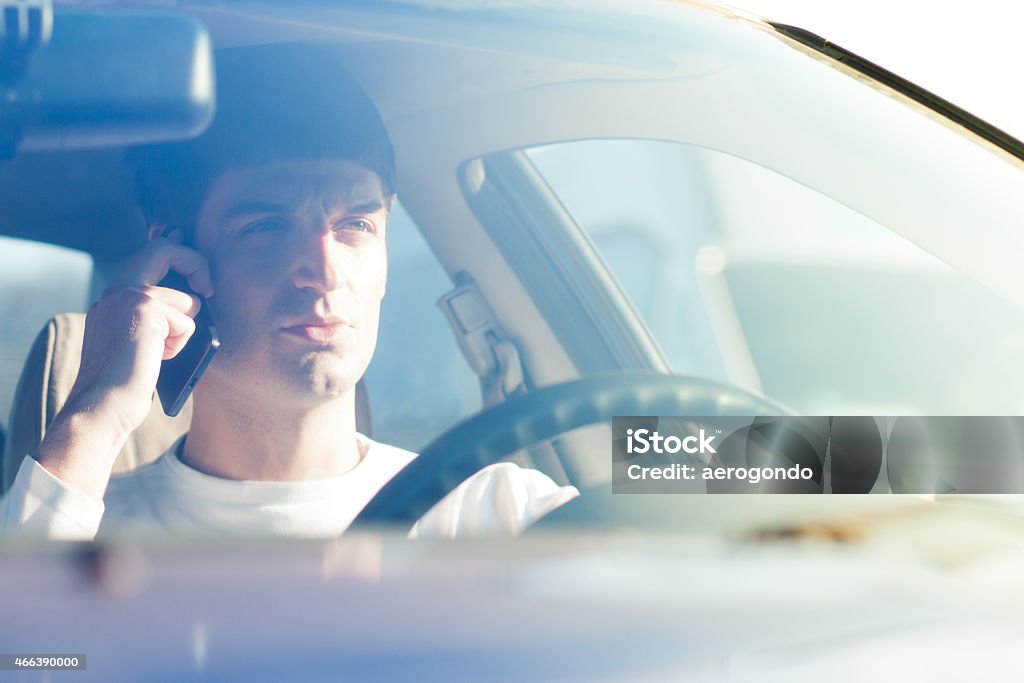 young man driving and using cell phone 2015 Stock Photo