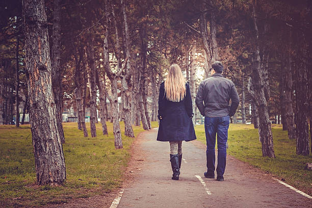vista traseira de um casal andando pelo parque da cidade de outono - middle human age couple women - fotografias e filmes do acervo