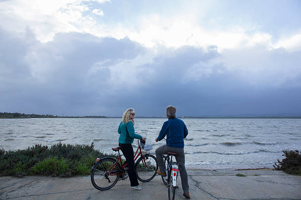 istock Biking couple pause by water edge, look out 466391912