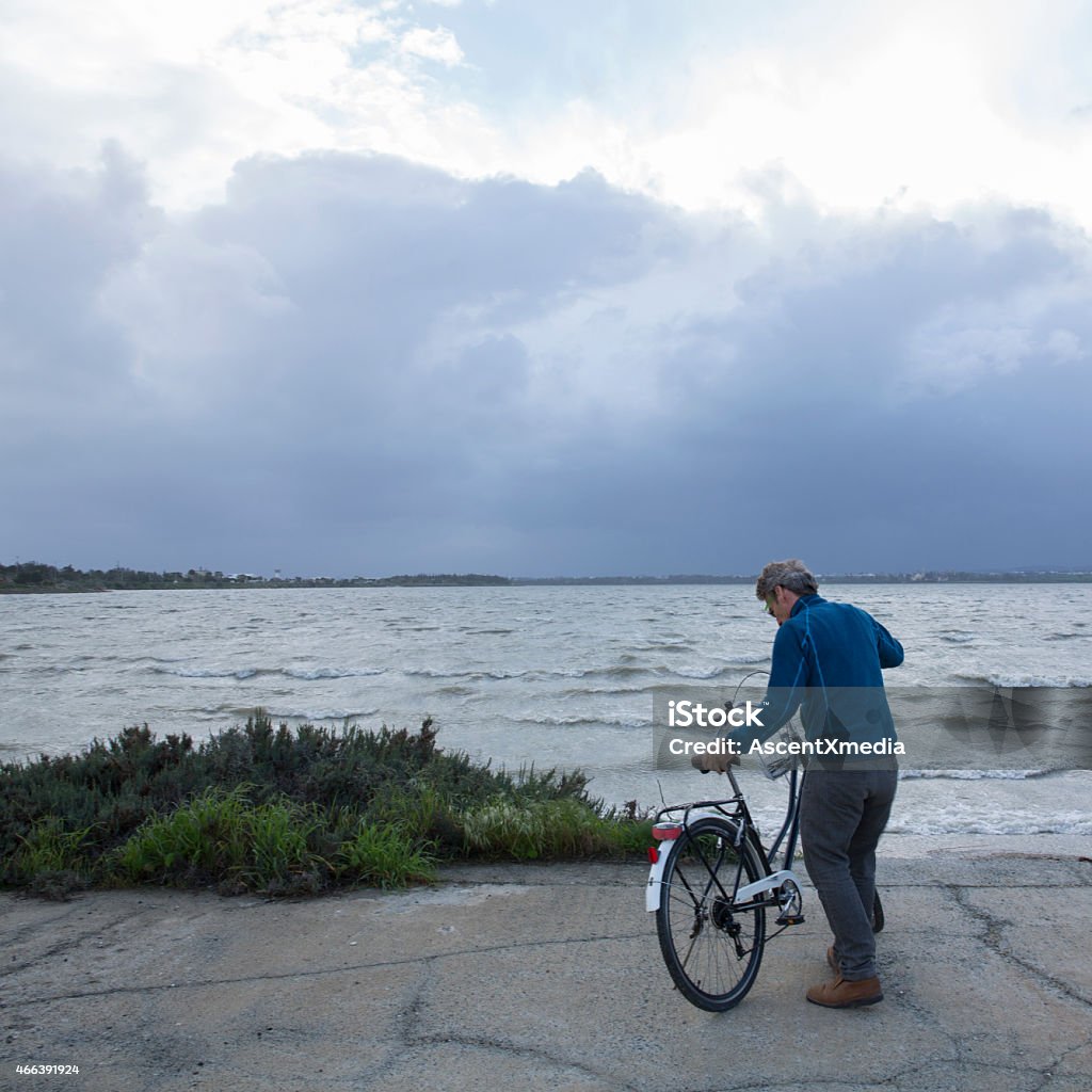 Biker pauses by water edge, prepares bike stand Admiration Stock Photo