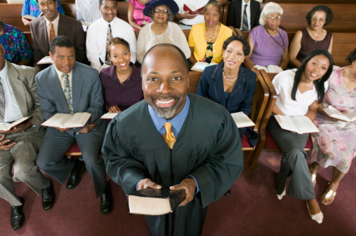 Portrait of confident preacher holding Bible with congregation sitting in church