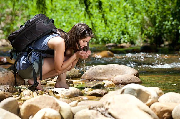 istock Woman drinking water from outdoor stream with her hands 466396660