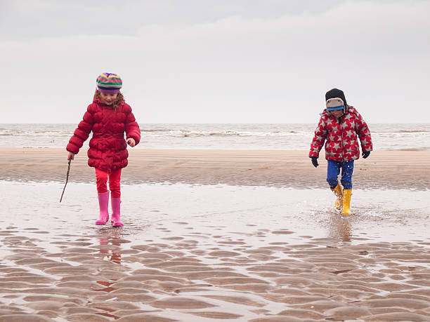 istock small boy and girl paddling on the beach 466397743
