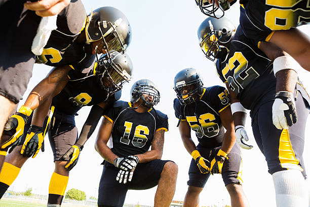 Football team huddled during time out while playing game Football team huddled during time out while playing game huddle stock pictures, royalty-free photos & images