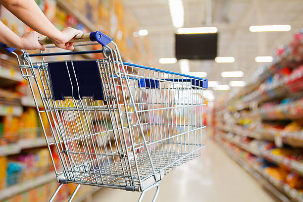 woman pushing shopping cart in supermarket woman pushing shopping cart in supermarket local products stock pictures, royalty-free photos & images