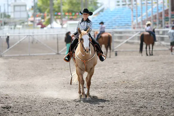 cowgirl contestant riding her horse in an arena during fair