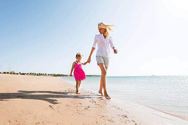 istock Mother and daughter walking on the beach during summer day. 466410948