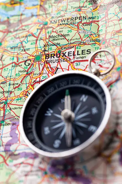 Compass on Europe map showing city Bruxelles. Shallow DOF, selective focus on compass.