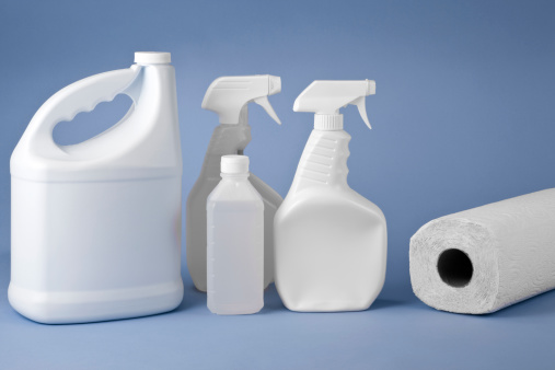 Cleaning bottles with paper towel roll on blue background.