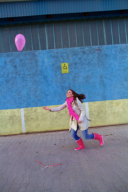 Woman in white coat, rainboots and pink balloons