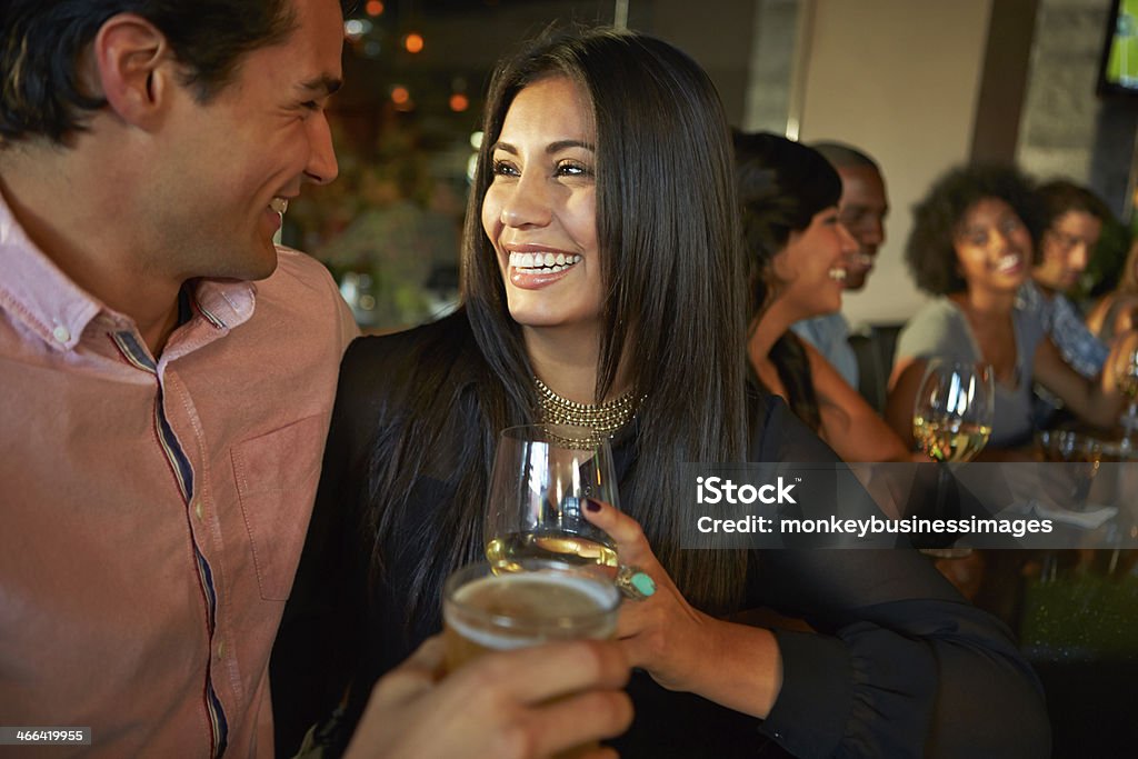 Couple Enjoying Drink At Bar With Friends Happy Smiling Couple Enjoying Drink At Bar With Friends 20-29 Years Stock Photo