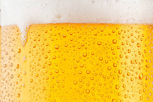 Beer Background     Ice Cold Pint With Water Drops Condensation Close up drops of a Ice Cold Pint of Beer, covered with water drops - condensation. The background is clear with the emphasis on water drops on yellow-golden background. frothy drink stock pictures, royalty-free photos & images