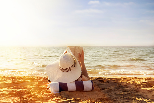 Beautiful young asian woman with hat arm up relaxing on beach chair, Summer happy beach vacation concept.