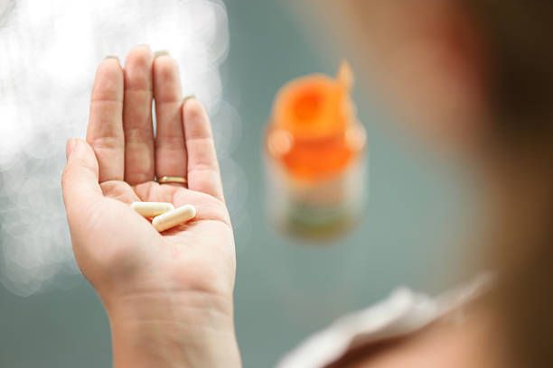 istock Young woman taking vitamins ginseng calcium pill 466428260