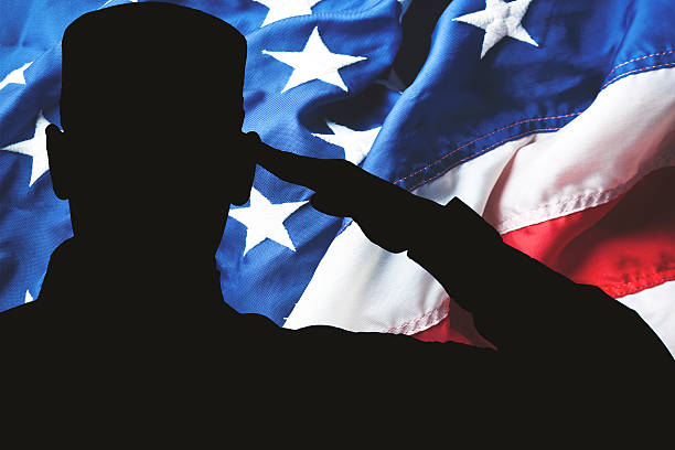 dumny salutować męskie żołnierz na tle flagi amerykańskiej - saluting armed forces military us veterans day zdjęcia i obrazy z banku zdjęć