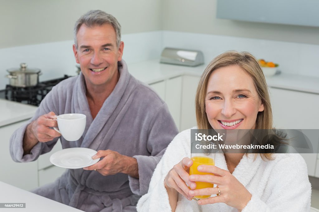 Smiling couple with orange juice and coffee in kitchen Portrait of a smiling couple with orange juice and coffee in the kitchen at home 2015 Stock Photo