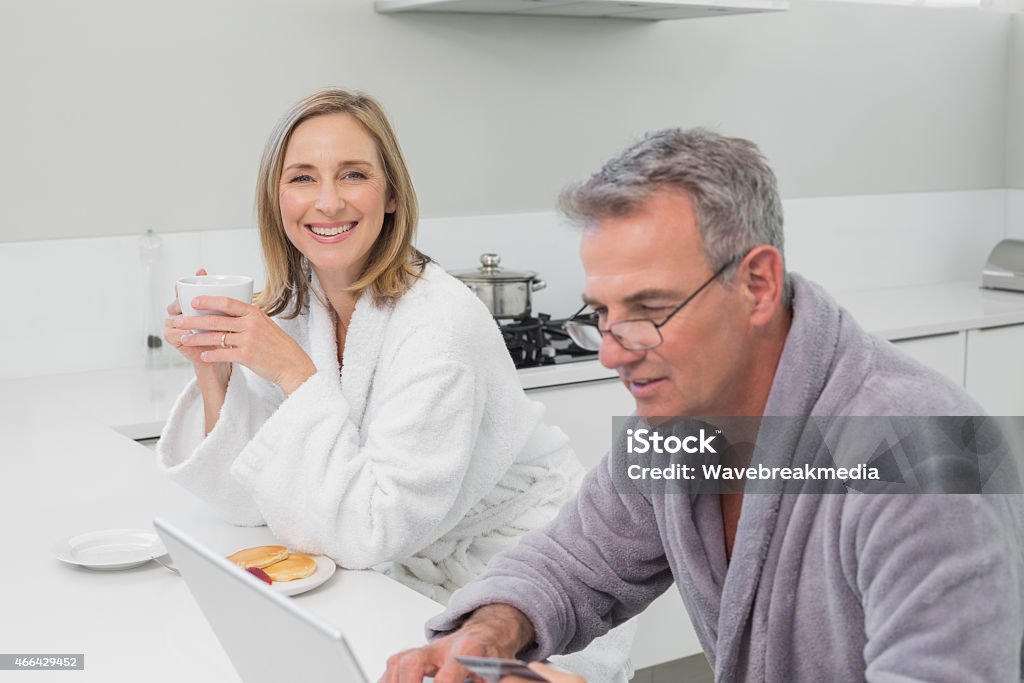 Happy couple in bathrobe doing online shopping at home Happy couple in bathrobe doing online shopping through laptop and credit card at home 2015 Stock Photo