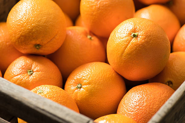 Navel Oranges in a Wooden Crate Navel Oranges in a wooden crate on a  black surface. navel orange photos stock pictures, royalty-free photos & images