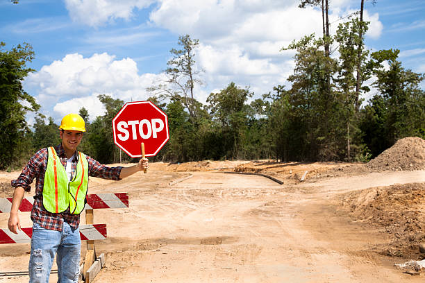 istock Road construction flagman.  He holds a stop sign. 466431465