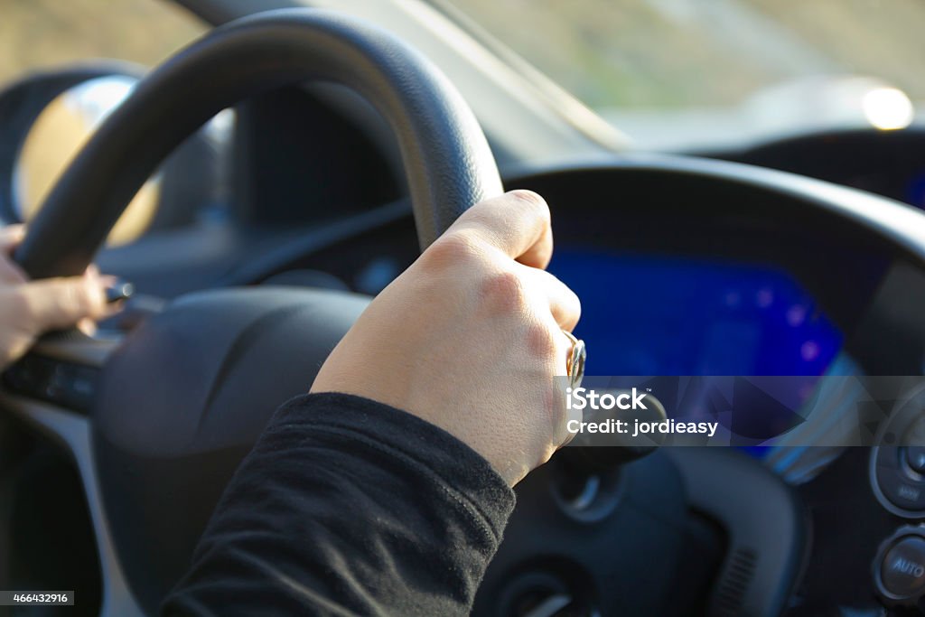 Driving a steering wheel car View of a steering wheel with hands driving a car. 2015 Stock Photo