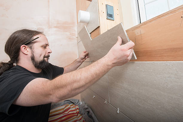 istock Tiler fixing cut tile to a wall in new bathroom 466433883