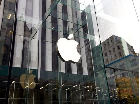 New York City, United States America - November 15, 2013: Glass entrance to the Apple Store in New York City store with people shopping for computers and yellow New York cabs in traffic.  United States based company