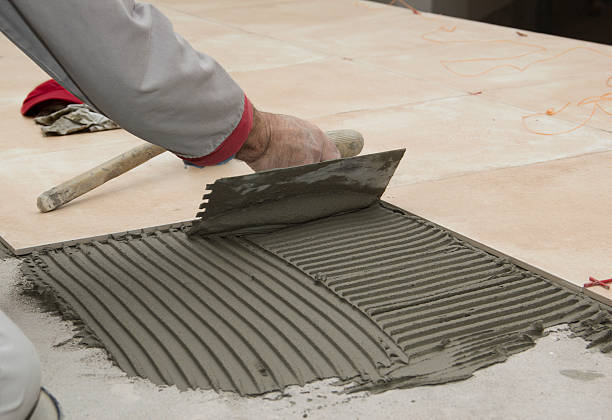 Home improvement, renovation - handyman laying tile with level stock photo