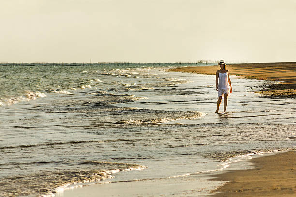 istock Beautiful Woman Dressed in White Walking Around Deserted Beach 466441812