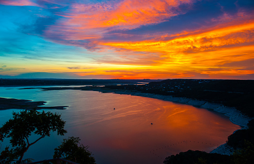 As the Sun sets over Travis Lake in Austin Texas. The Oasis view from the high overlook shows Lake Travis with an amazing once in a lifetime sunset that brings vibrant colors all over the sky. Lake Travis looks like paradise as the colors of the atmosphere reflect over the water.  