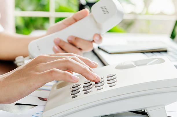 Dialling on a telephone Woman dialling on a telephone in an office dialling phone stock pictures, royalty-free photos & images