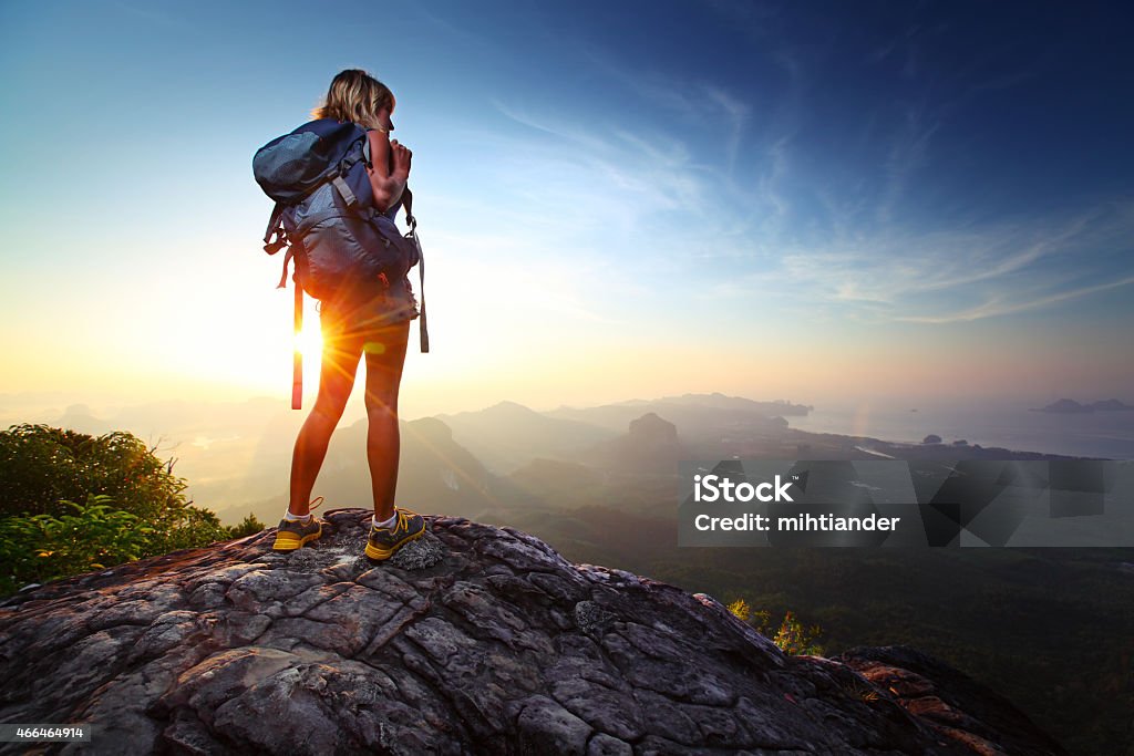 Hiker Young lady hiker standing with backpack on top of a mountain and enjoying sunrise Hiking Stock Photo