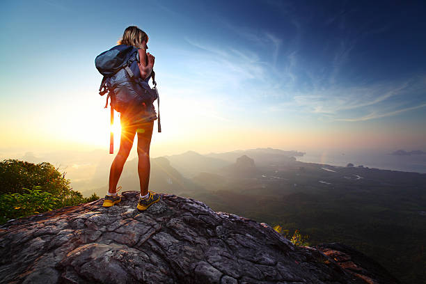 Hiker Young lady hiker standing with backpack on top of a mountain and enjoying sunrise view from mountain top stock pictures, royalty-free photos & images