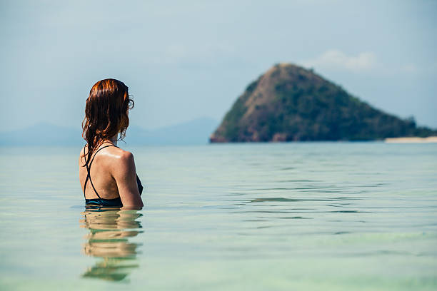 istock Woman sitting in water looking at island 466465646